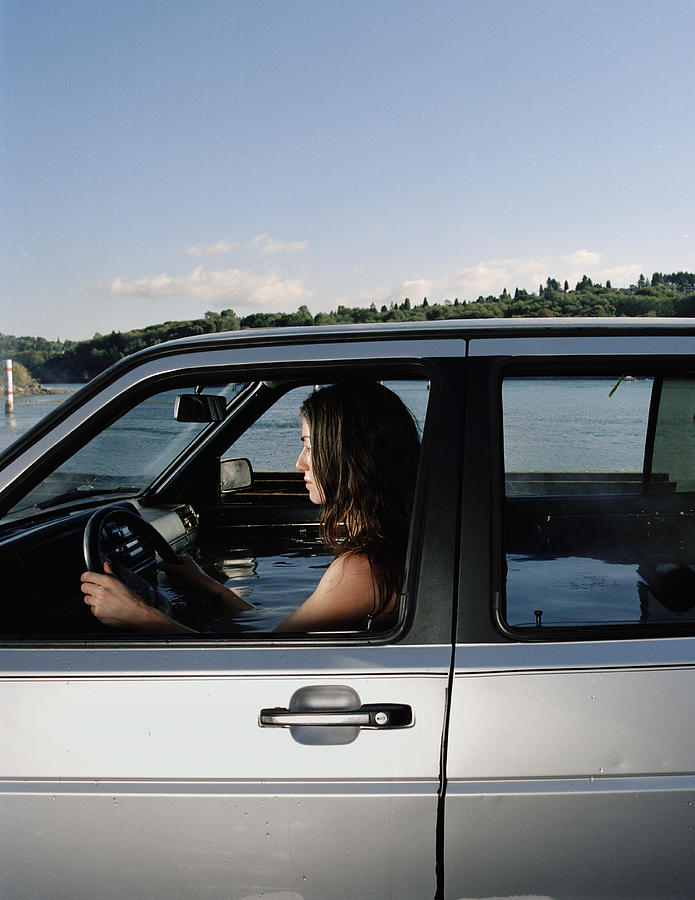 Woman in car filled with water, side view Photograph by Matthias Clamer