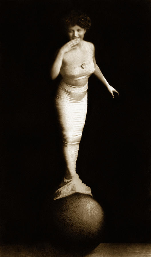 Woman in mermaid costume balancing on ball Photograph by Brand X Pictures