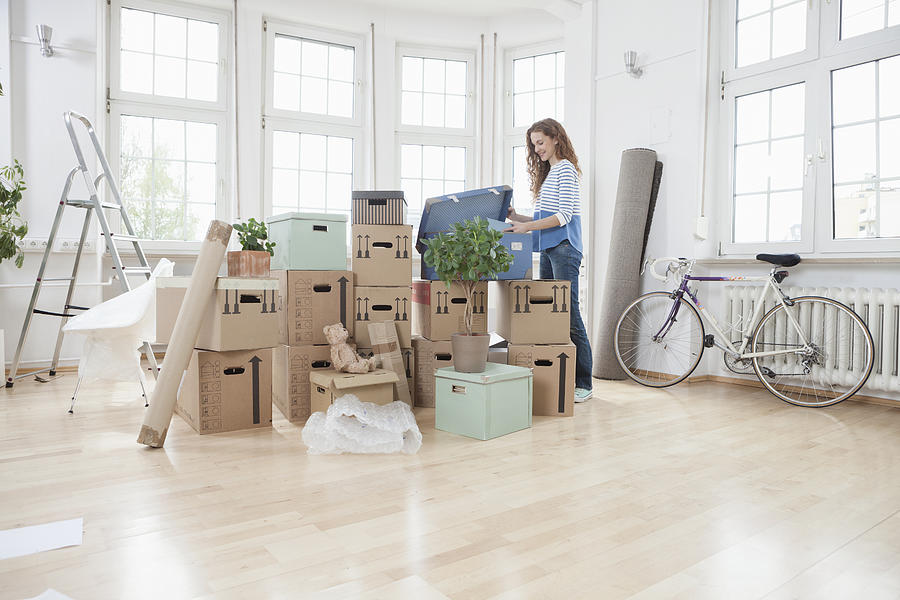 Woman in new apartment unpacking cardboard box Photograph by Westend61