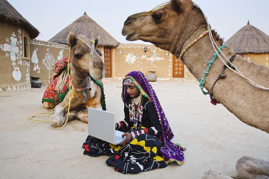 Woman in sari by camels with laptop computer Photograph by Jami Tarris