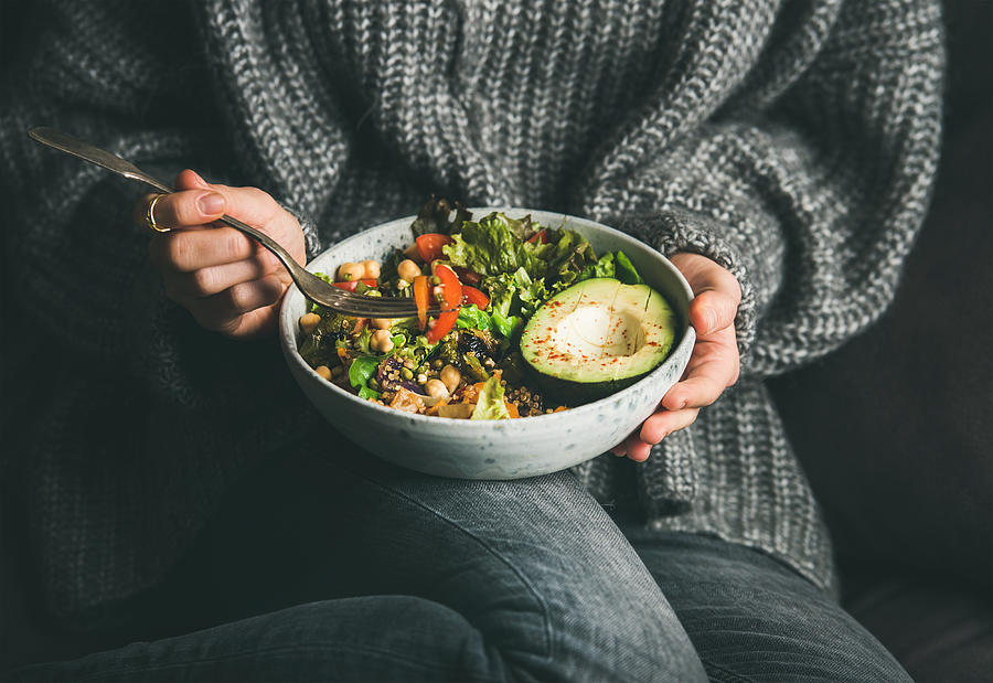 Woman in sweater eating fresh salad, avocado, beans and vegetables Photograph by Foxys_forest_manufacture