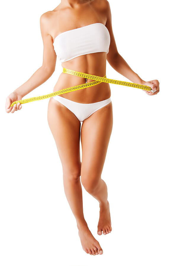 Woman in white using yellow measuring tape on waist Photograph by Brainsil