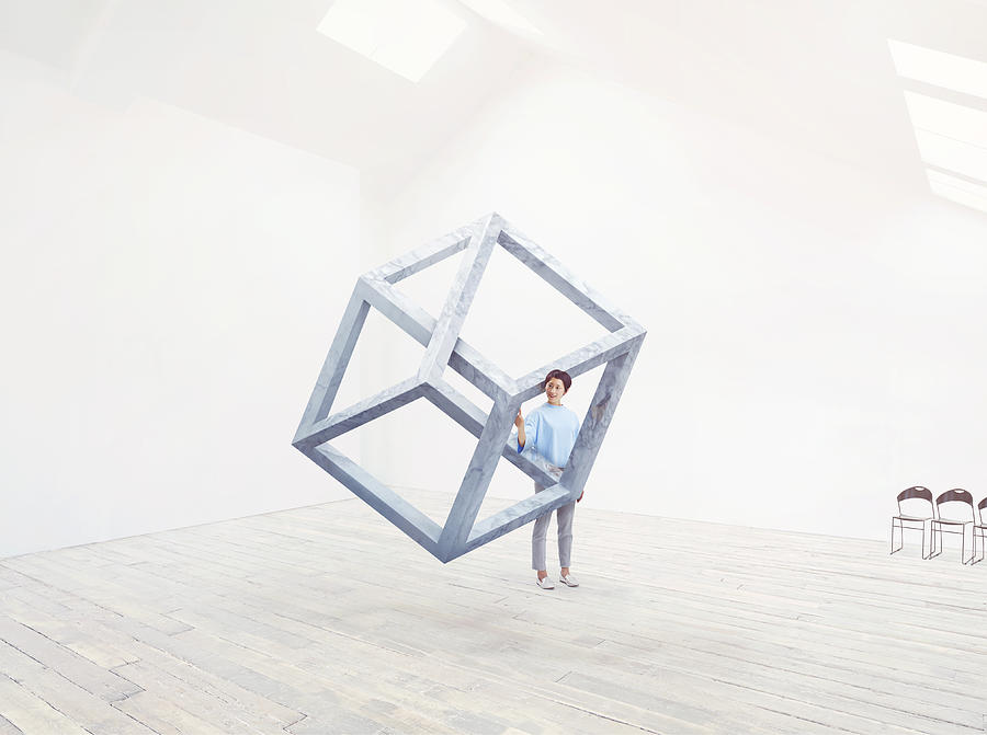 Woman interacting with an impossible cube. Photograph by Ezra Bailey