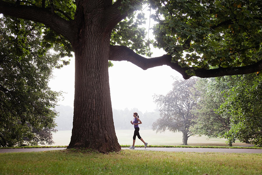 Woman jogging in suburban park Photograph by PM Images