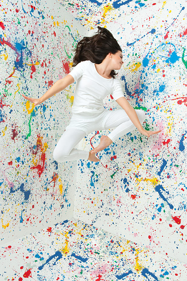 Woman jumping and walls covered in paint Photograph by Image Source