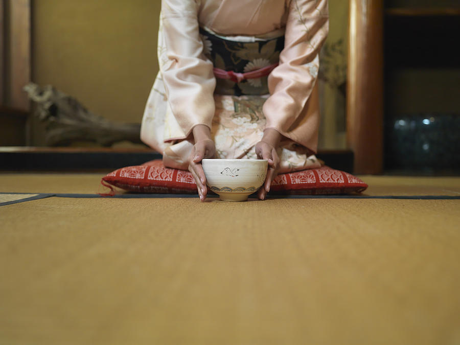 Woman kneeling down tea bowl, mid section Photograph by Michael H