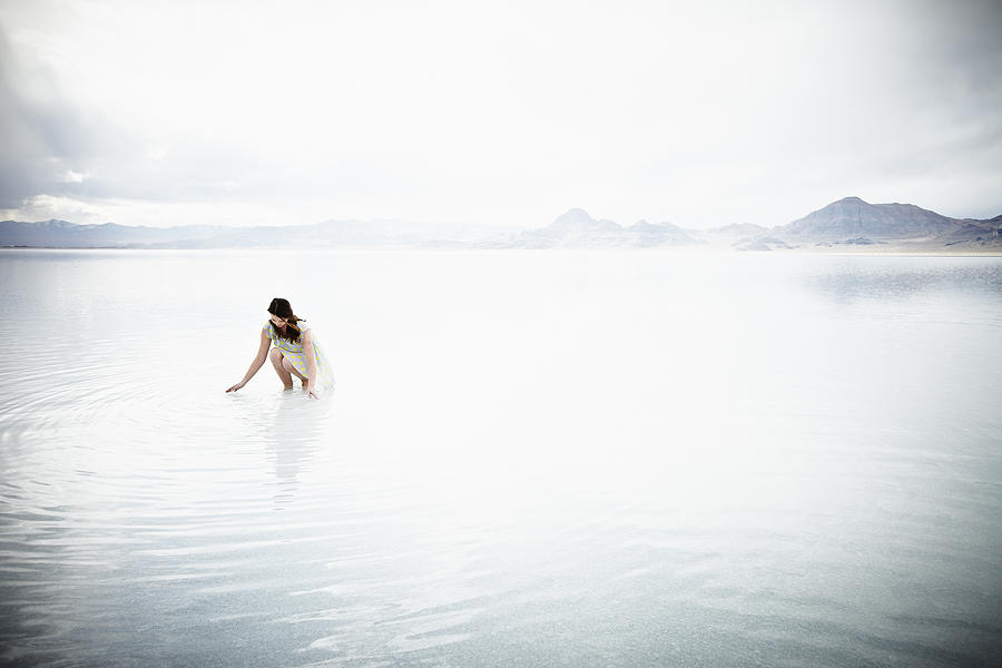 Woman kneeling with hands touching water Photograph by Thomas Barwick