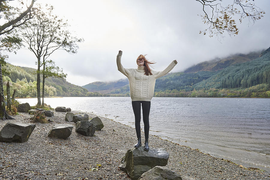 Woman laughing by the side of a loch Photograph by Plume Creative