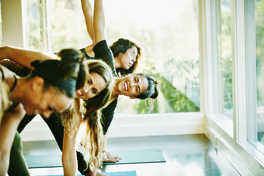 Woman laughing with friends during yoga class Photograph by Thomas Barwick