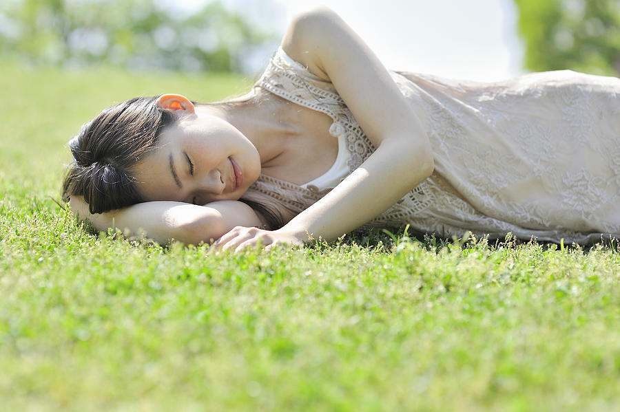 Woman laying down in nature, eyes closed Photograph by Yagi Studio