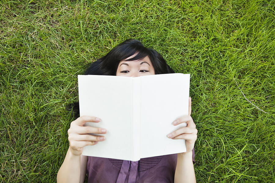 Woman Laying In Grass Reading A Book Photograph by Compassionate Eye Foundation/Justin Pumfrey
