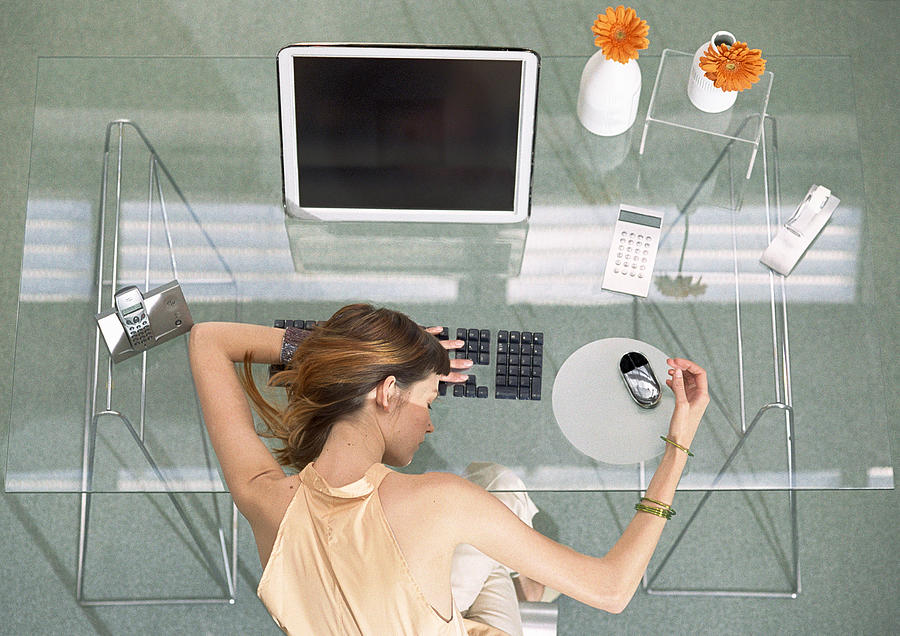 Woman leaning head on desk with futuristic devices, high angle view Photograph by Coco Marlet