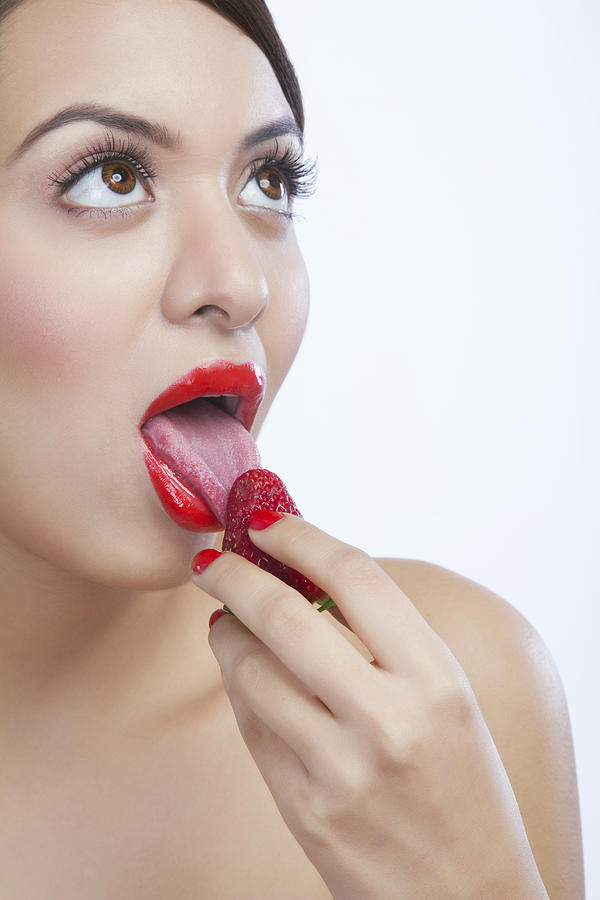 Woman licking a strawberry Photograph by IndiaPix/IndiaPicture