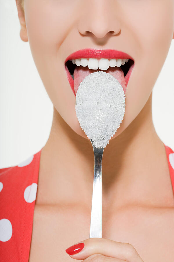 Woman licking a sugary spoon Photograph by Image Source