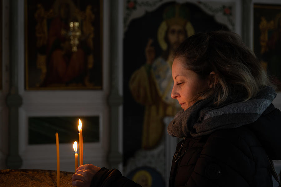 Woman lighting a candle in a Greek Orthodox church Photograph by George Pachantouris
