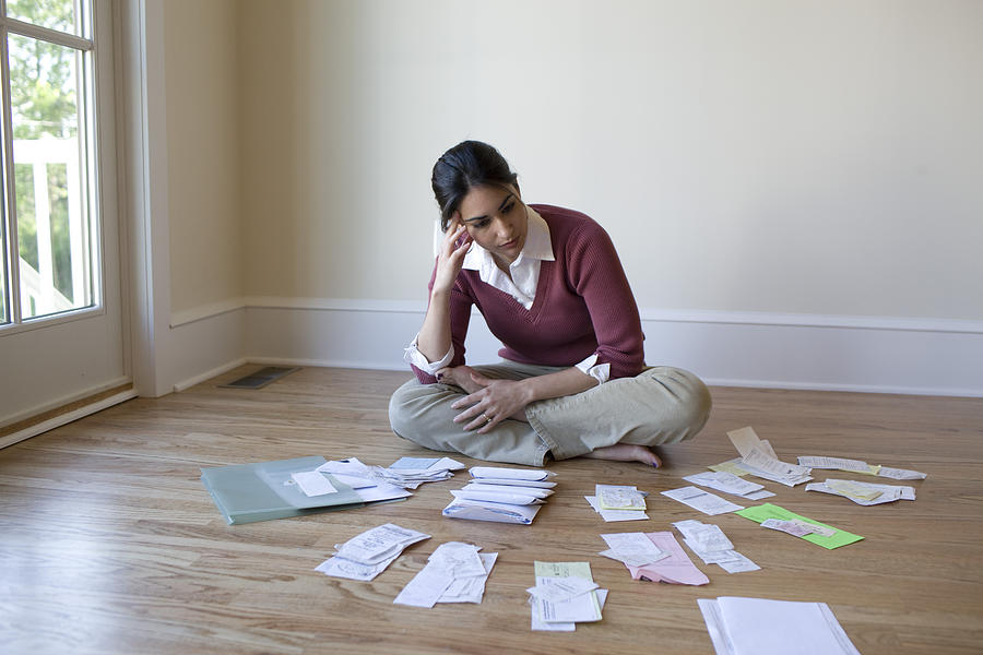Woman looking at bills and receipts on floor Photograph by David Sacks