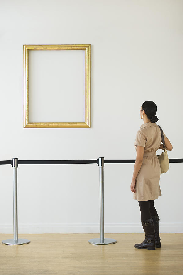 Woman looking at blank picture frame in art gallery Photograph by Tetra Images