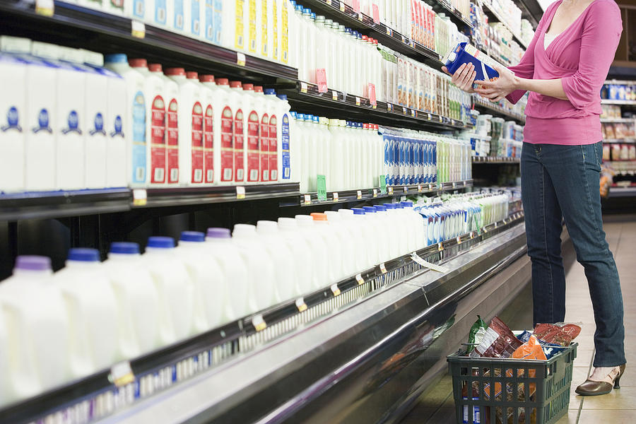 Woman looking at milk carton in supermarket, low section Photograph by Paul Burns