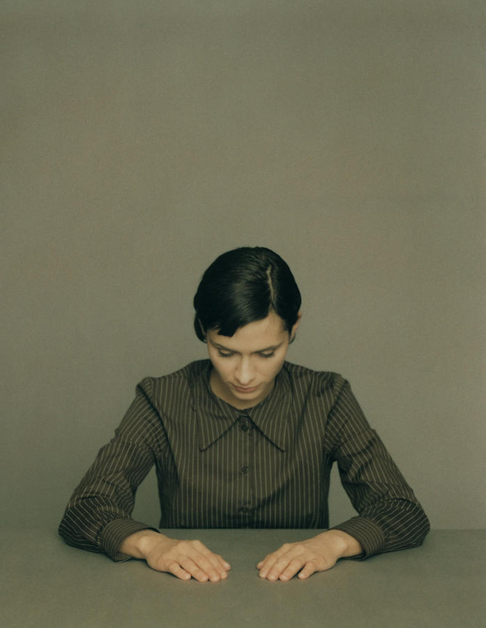 Woman looking down with arms extended forward and resting on table, portrait Photograph by Matthieu Spohn