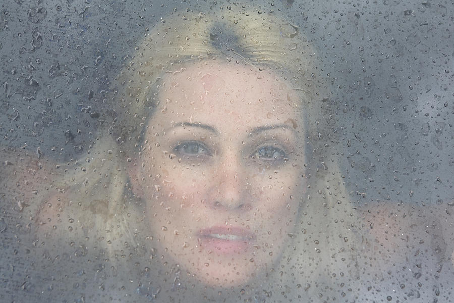 Woman looking through a rain drop window Photograph by George Shelley Productions