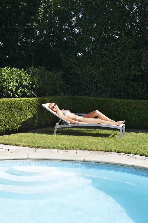 Woman Lying on a Sun Lounger by a Swimming Pool Photograph by Digital Vision.