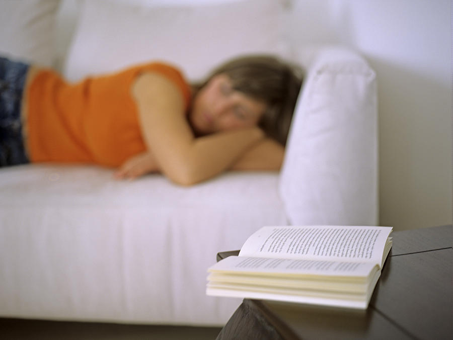 Woman lying on sofa, focus on open book Photograph by Daniel Krolls