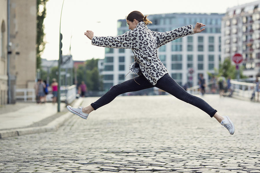 Woman Making A Big Jump In A Sunny City Street Photograph by Justin Case
