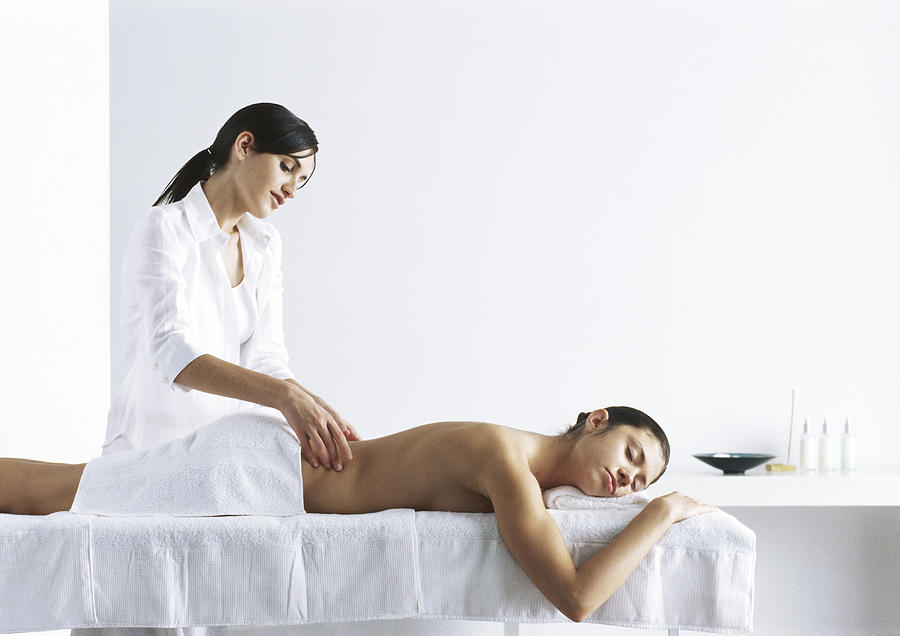 Woman massaging second woman on massage table Photograph by Frederic Cirou