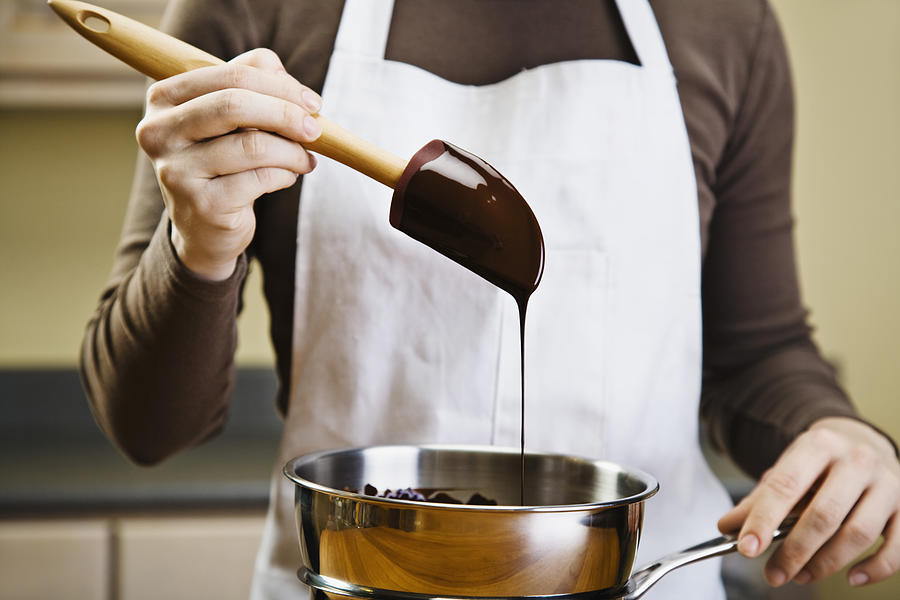 Woman melting chocolate in double boiler Photograph by Jupiterimages
