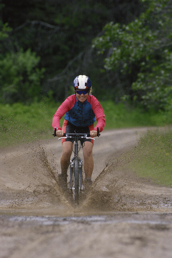 Woman mountain biking through the mud in British Columbia , Canada Photograph by Comstock