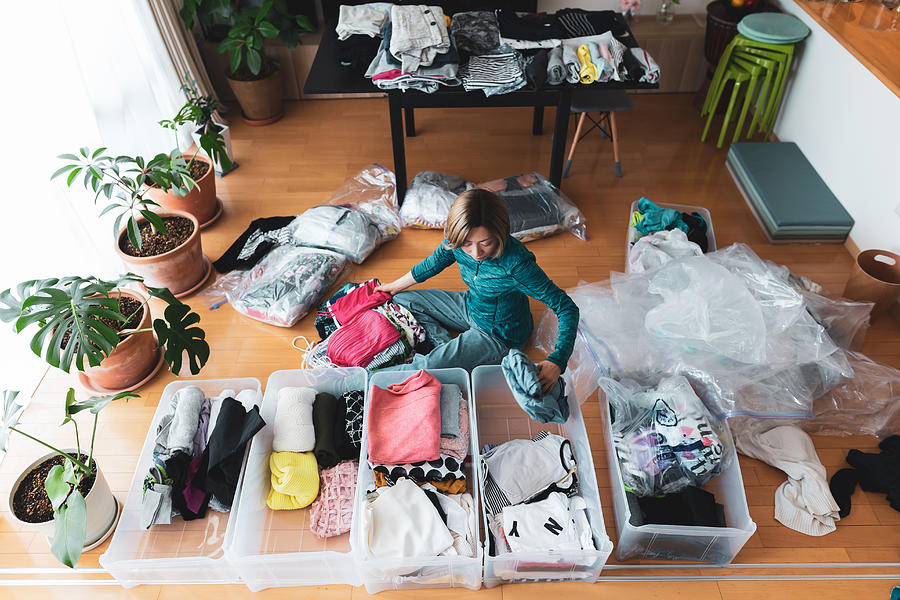 Woman organizes clothes in living room of her home Photograph by Susumu Yoshioka