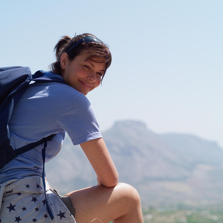 Woman outdoors wearing backpack, looking over shoulder, portrait Photograph by Phil Boorman