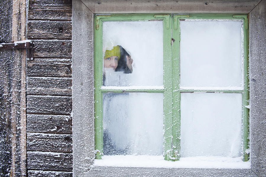 Woman peering out frosty window Photograph by Lars Forsstedt