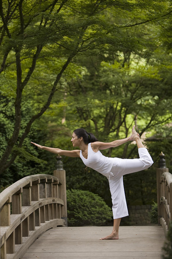 Woman performing yoga on bridge in Japanese garden Photograph by John Giustina