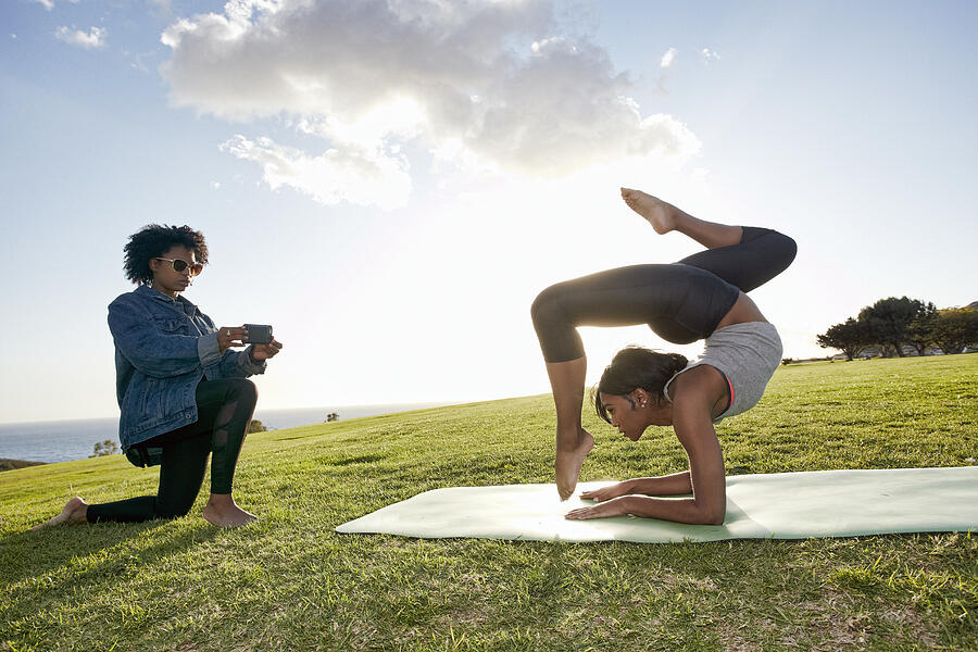 Woman Photographing Female Friend Doing Yoga Photograph by Peathegee Inc
