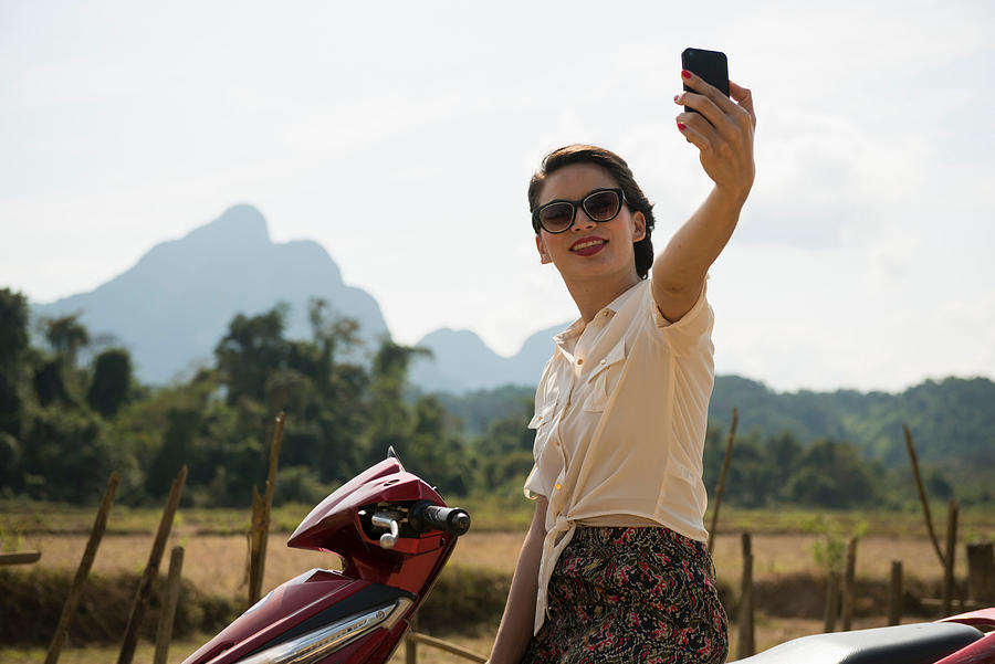 Woman photographing self on moped, Vang Vieng, Laos Photograph by Ben Pipe Photography