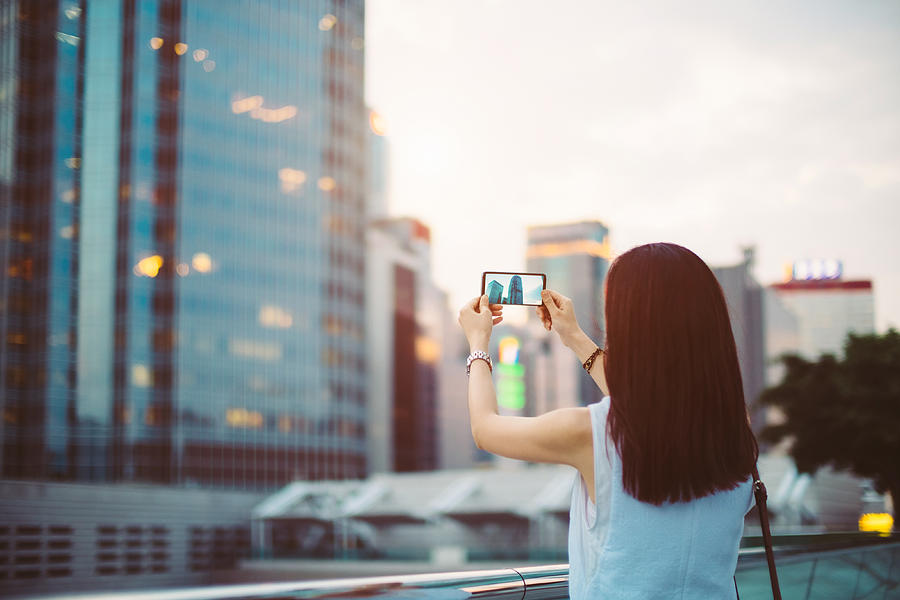 Woman photographing with smartphone in Central Business District of Hong Kong Photograph by D3sign