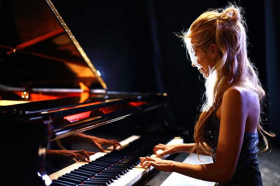 Woman playing piano in a concert. Photograph by Gilaxia