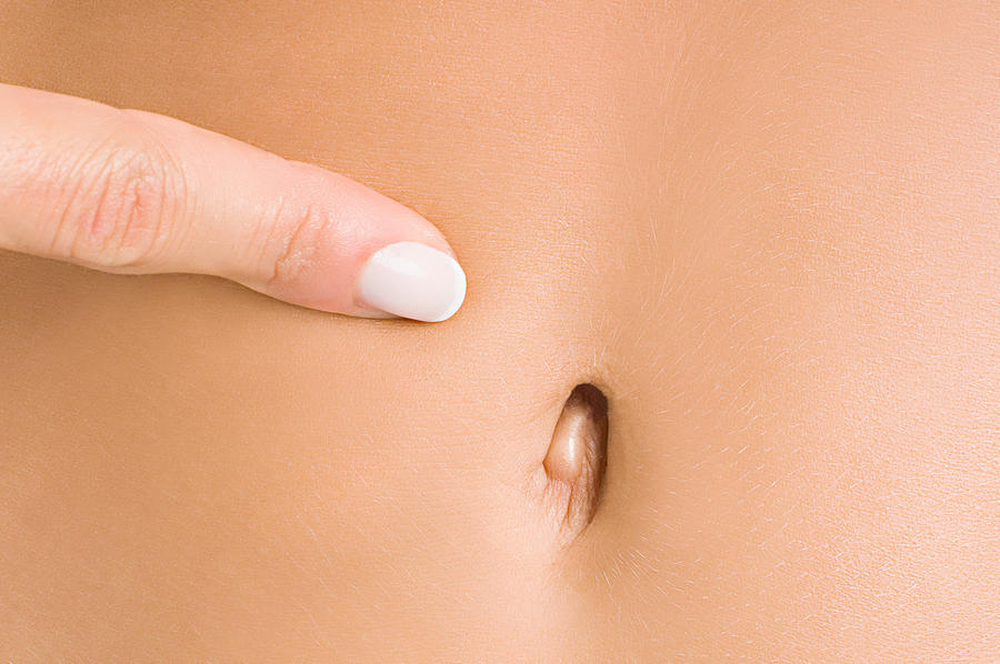 Woman pointing to navel Photograph by Image Source