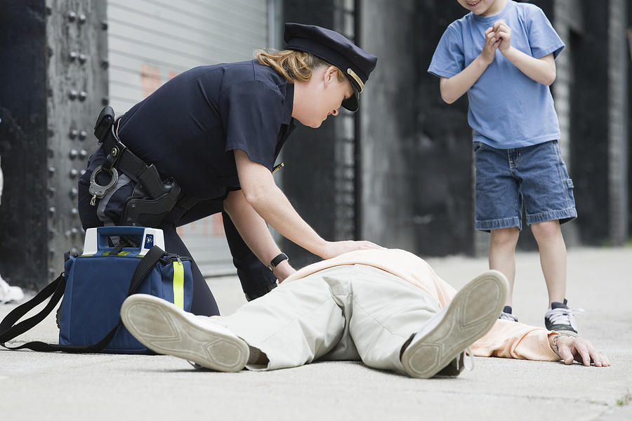 Woman police officer administering first aid to a senior man Photograph by Huntstock