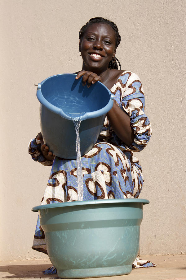 Woman pours water in bucket Photograph by Commerceandculturestock