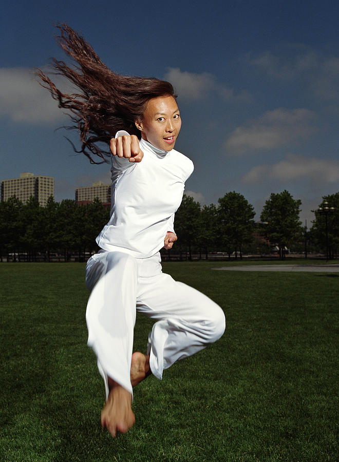 Woman practicing tae kwon do in park (blurred motion) Photograph by PM Images
