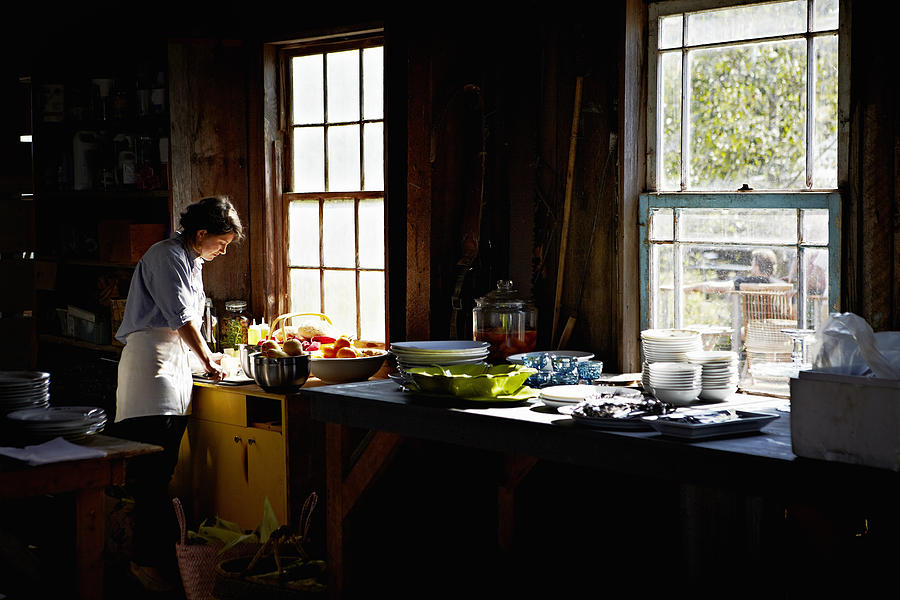 Woman preparing for party in vacation home kitchen Photograph by Thomas Barwick