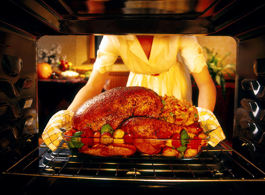 Woman preparing roasted turkey in oven Photograph by Lew Robertson