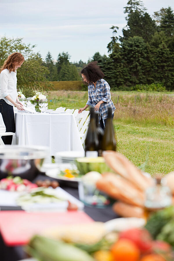 Woman preparing table for dinner party on farm Photograph by Image Source