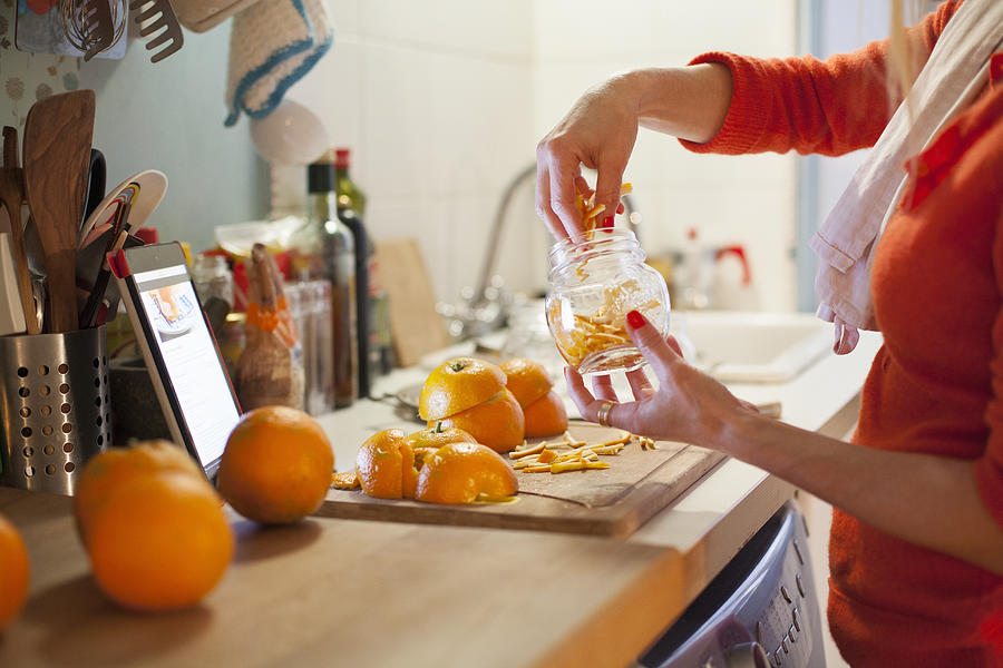 Woman preparing to make orange marmalade, filling jar with thinly cut orange zest Photograph by Kathrin Ziegler