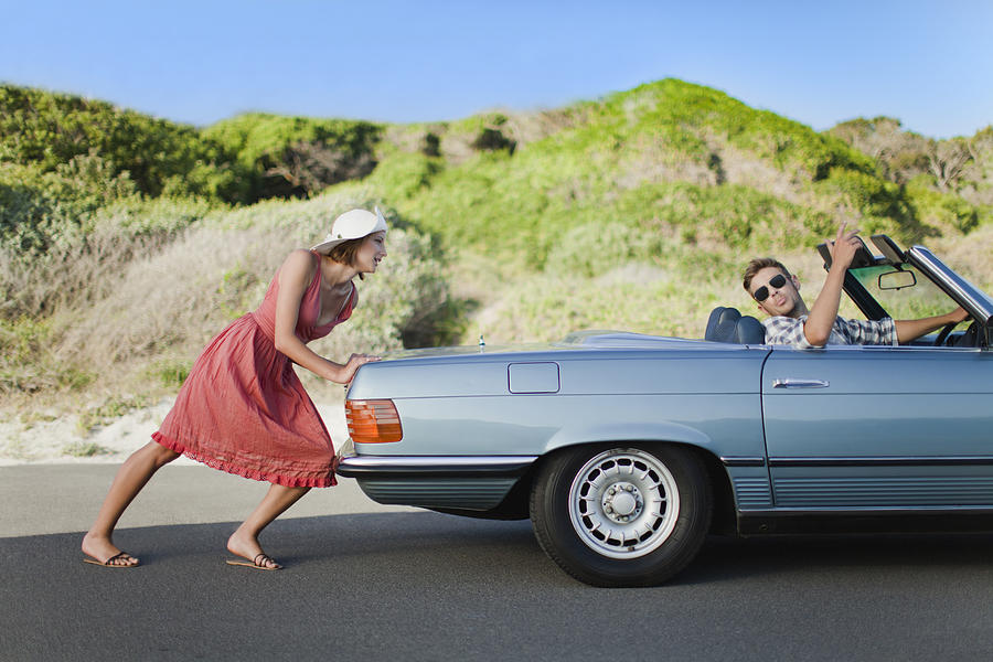 Woman pushing car as boyfriend steers Photograph by Hybrid Images