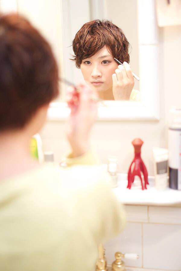 Woman putting on make-up Photograph by Tadamasa Taniguchi