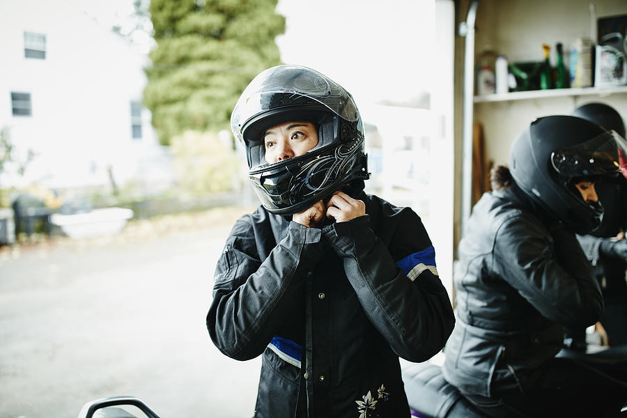 Woman putting on motorcycle helmet before ride Photograph by Thomas Barwick