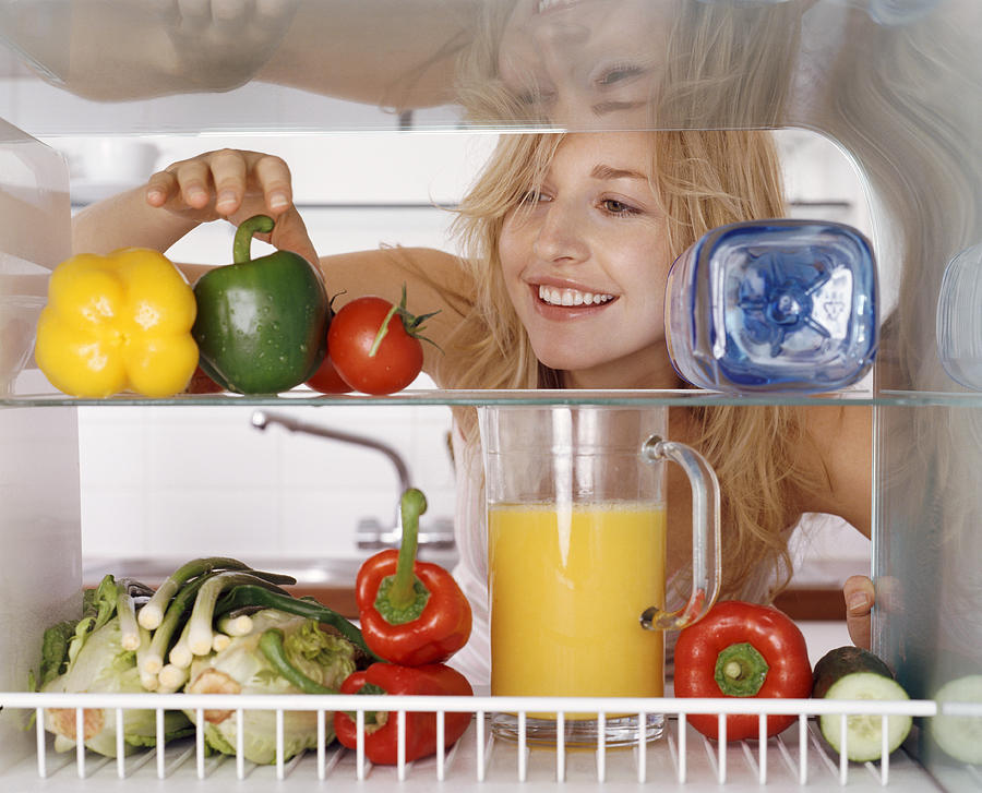 Woman Reaching for a Green Pepper in a Fridge Photograph by Bill Ling